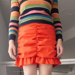 Coral red miniskirt with ruching and ruffled hem.